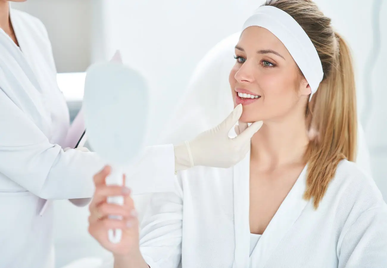 Woman looking at her medical spa treatment results in a handheld mirror