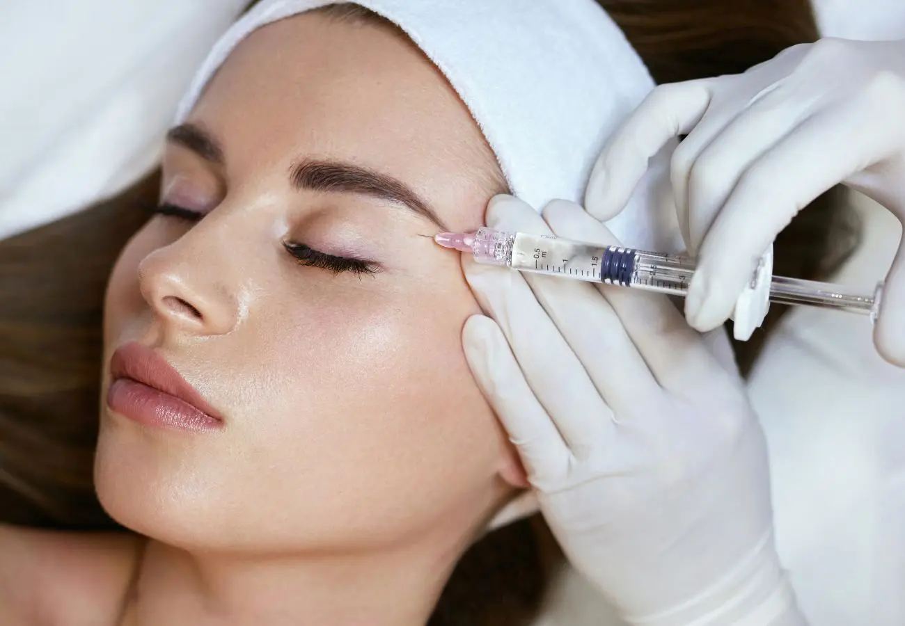 Closeup of woman's face with a syringe receiving face fillers