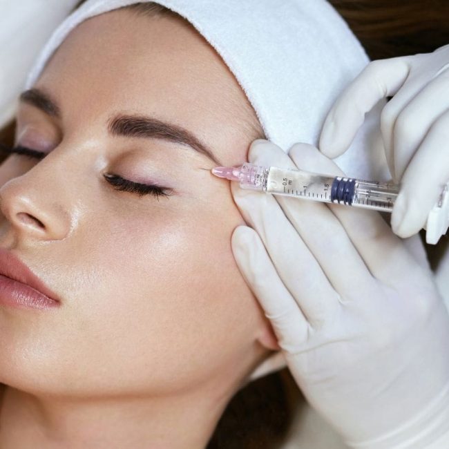 Closeup of woman's face with a syringe receiving face fillers
